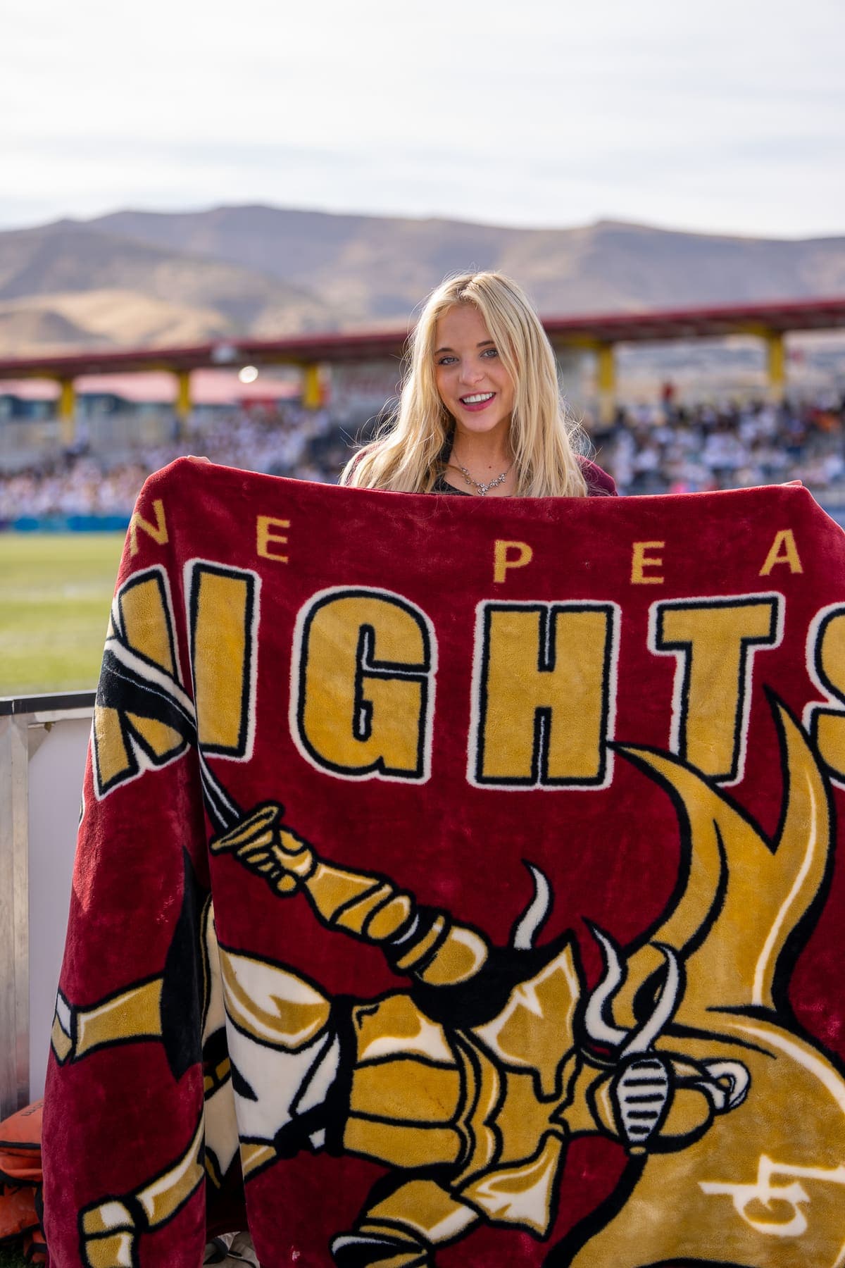 A student holding up a finished custom printed Knights spirit blanket at a stadium
